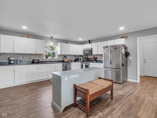 kitchen with vinyl plank floors, backsplash, dark countertops, white cabinets, and appliances with stainless steel finishes | Image 8