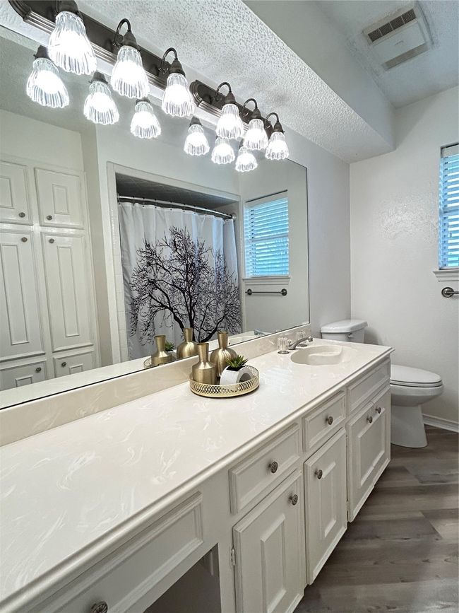Bathroom featuring vanity, wood finished floors, visible vents, a textured ceiling, and toilet | Image 24