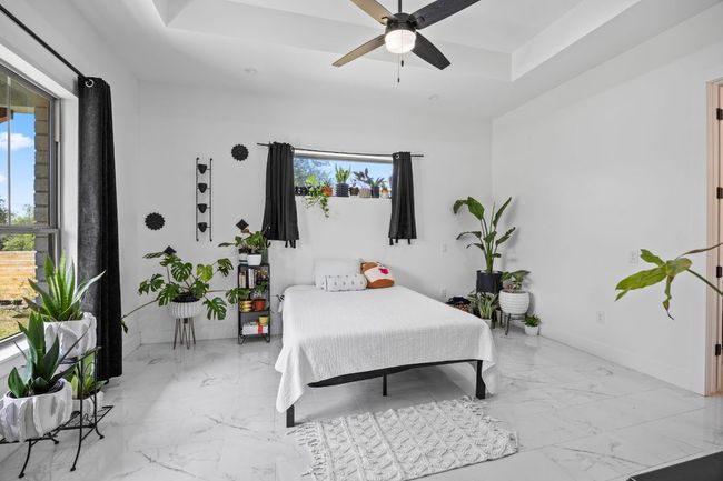 Bedroom featuring light tile floors, multiple windows, and a raised ceiling | Image 17