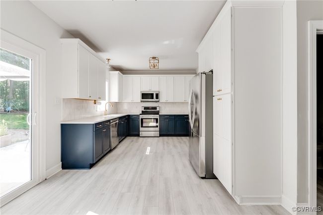 Totally upgraded kitchen with stainless steel appliances, blue cabinetry, white cabinets, and light countertops | Image 12