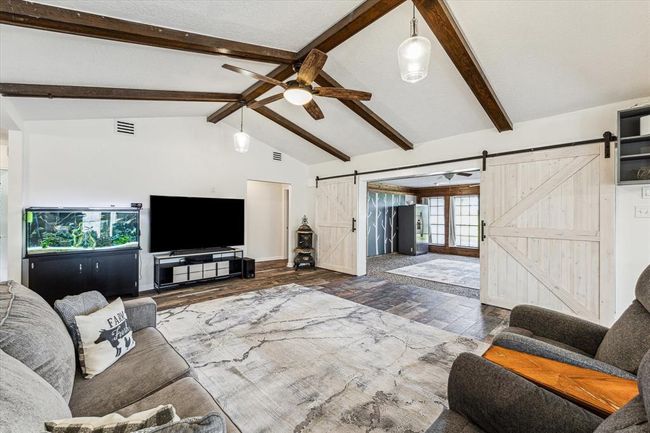 The main living area is the heart of the home, with its high wood-beamed ceilings and inviting features. The double barn doors leading to the sunroom add both functionality and style, allowing for flexibility in the use of space while maintaining a cohesive design aesthetic. Closing off the sunroom with these doors offers privacy when desired while seamlessly integrating it into the overall living area when open | Image 19