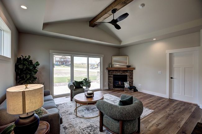 Living area featuring recessed lighting, wood finished floors, a stone fireplace, ceiling fan, and a tray ceiling | Image 16