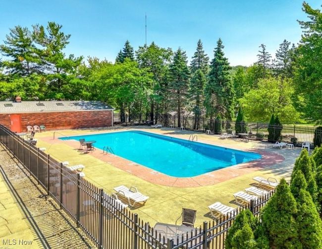 Community pool with a patio area and view of wooded area | Image 29