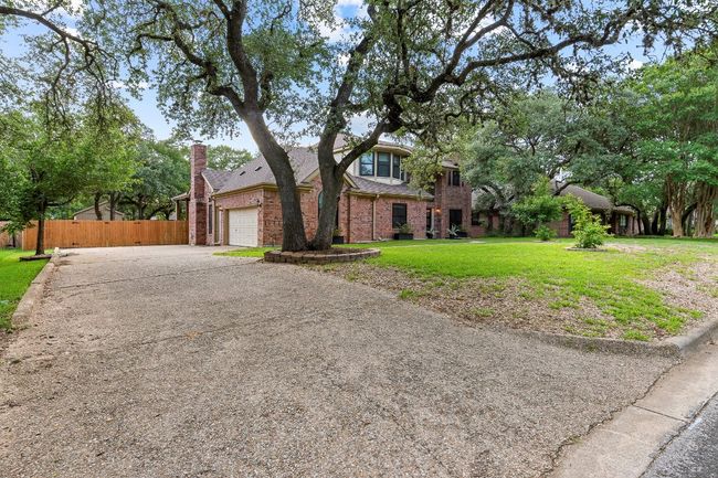 View of front facade with driveway, brick siding, a garage, roof with shingles, and a chimney | Image 5