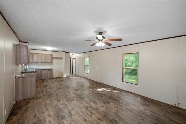 Unfurnished living room featuring ceiling fan, dark wood finished floors, and plenty of natural light | Image 19