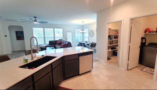 Kitchen featuring dishwasher, light countertops, ceiling fan, open floor plan, and arched walkways | Image 12