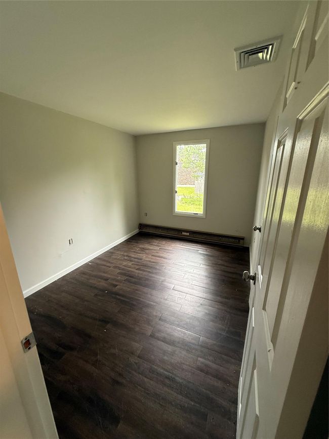 Empty room with baseboard heating, dark wood-type flooring, and baseboards | Image 4