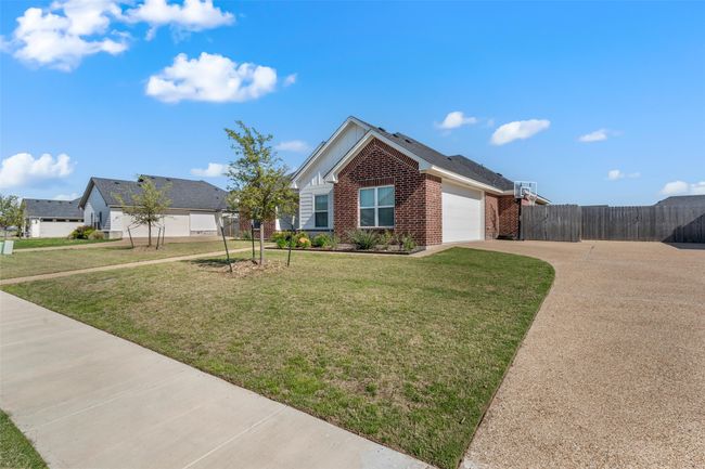 Single story home featuring driveway, a front lawn, brick siding, a garage, and fence | Image 22