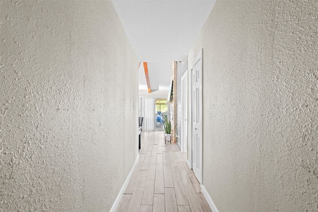 Corridor with light wood-type flooring, a textured wall, and baseboards | Image 25