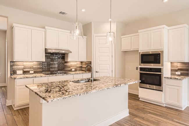 Kitchen with oven, a sink, built in microwave, light wood-style floors, and under cabinet range hood | Image 13