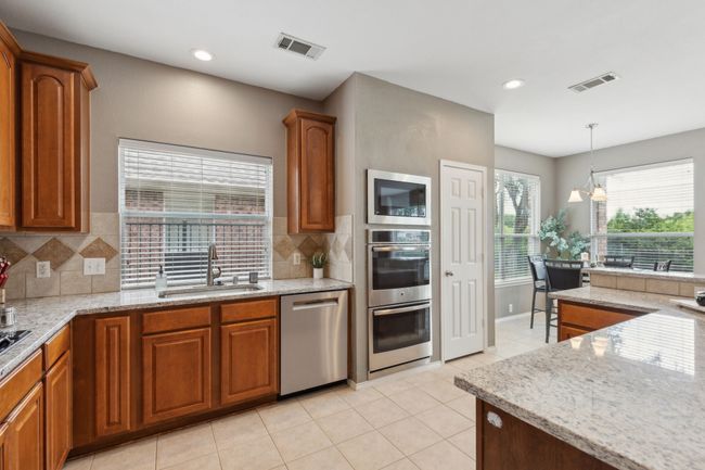 Kitchen with appliances with stainless steel finishes, a sink, brown cabinetry, and recessed lighting | Image 8