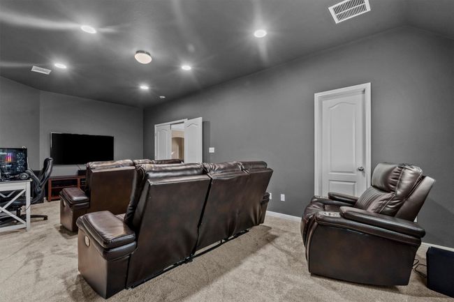 A spacious and light-filled bonus living area offers versatility for lounging, play, or casual entertaining—elevated by rich wood flooring and tray ceilings. | Image 27