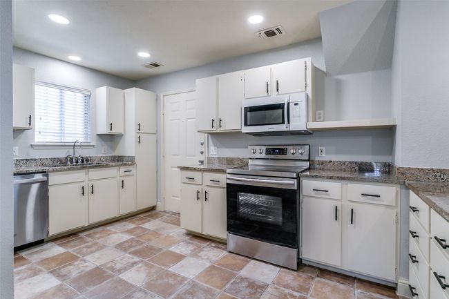 Kitchen featuring stainless steel appliances, white cabinetry, open shelves, light stone finish flooring, and recessed lighting | Image 11
