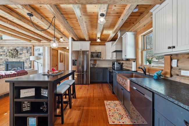 With leathered granite, copper sink, two-toned cabinets, black stainless steel appliances and hardwood floors | Image 6