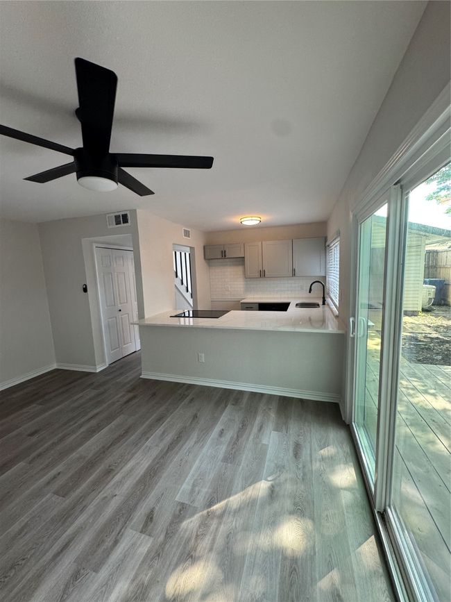 Kitchen with a sink, wood finished floors, a ceiling fan, baseboards, and cooktop | Image 6