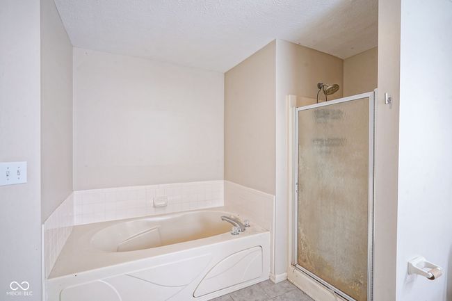 bathroom featuring a textured ceiling, a stall shower, a garden tub, and tile patterned floors | Image 26