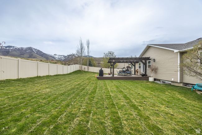 View of yard featuring a pergola, deck, fence, and a mountain view | Image 36