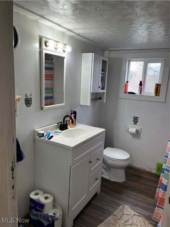Bathroom featuring vanity, a textured ceiling, toilet, and wood finished floors | Image 12