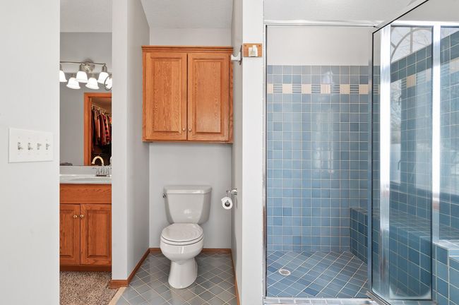There is a convenient walk-in shower with a built-in bench seat and a nice storage cabinet for bathroom essentials. | Image 22