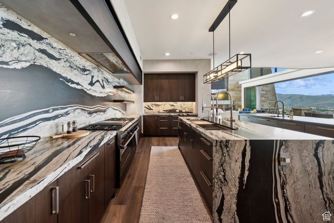 Kitchen featuring premium range hood, dark wood-type flooring, a sink, range with two ovens, and backsplash | Image 14