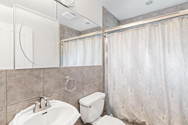 Bathroom featuring a sink, tile walls, toilet, and a shower with curtain | Image 35