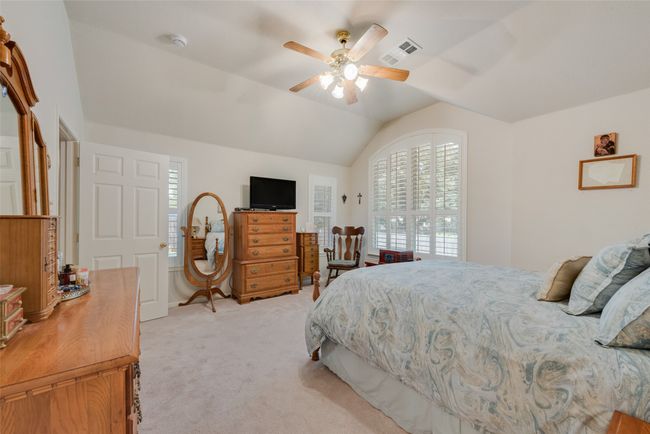 Bedroom featuring light colored carpet, lofted ceiling, and ceiling fan | Image 23