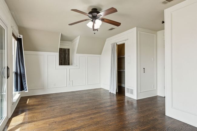 Additional living space with ceiling fan, visible vents, dark wood finished floors, and a decorative wall | Image 24