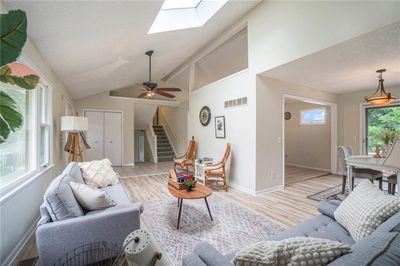 Tiled living room with ceiling fan and lofted ceiling with skylight | Image 1