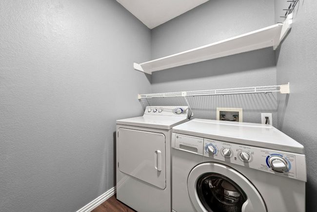Washroom featuring washing machine and clothes dryer, a textured wall, dark wood-style floors, and baseboards | Image 13