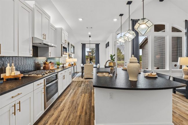 Kitchen with stainless steel appliances, under cabinet range hood, dark countertops, wood finished floors, and recessed lighting | Image 10