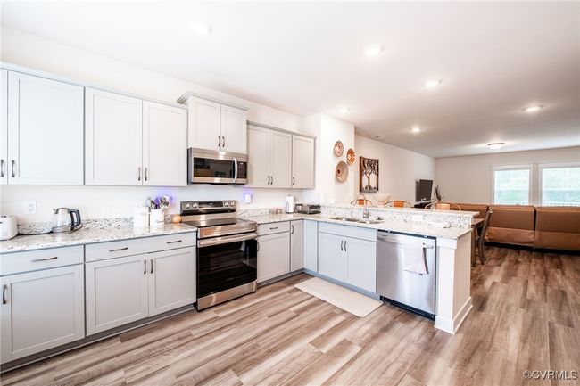 Kitchen with appliances with stainless steel finishes, open floor plan, a peninsula, light wood-type flooring, and recessed lighting | Image 11