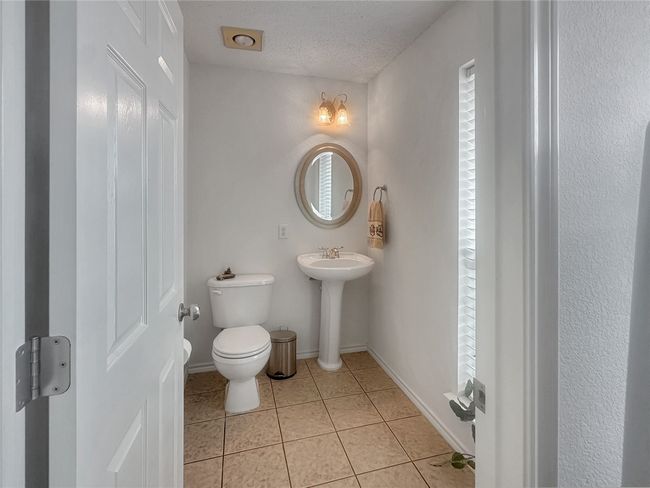Half bathroom with toilet, tile patterned floors, a textured ceiling, and baseboards | Image 20