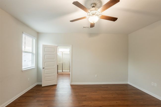 Empty room with baseboards, a ceiling fan, dark wood finished floors, and visible vents | Image 22