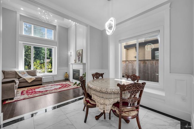 Dining area with light marble finish flooring, a decorative wall, a glass covered fireplace, and a wainscoted wall | Image 10