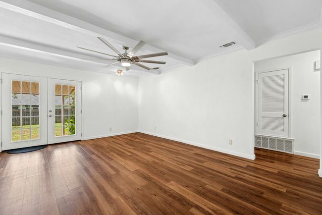 Living room featuring beamed ceiling, hardwood / wood-style flooring, new ceiling fan, French doors, and crown molding | Image 5