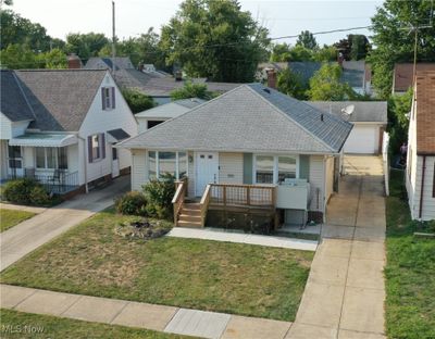 Bungalow-style house with a garage, a front lawn, and an outbuilding | Image 1