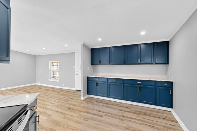 Kitchen with blue cabinets, light wood-style flooring, baseboards, ornamental molding, and light Granite countertops with luxury back splash. | Image 16