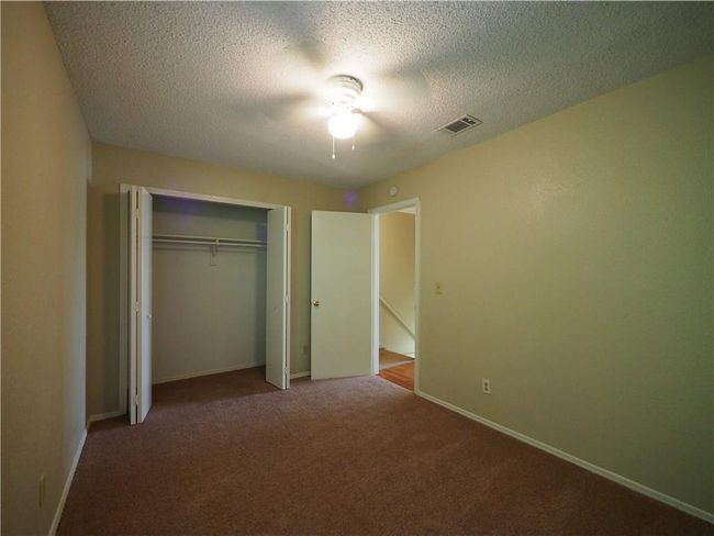 Unfurnished bedroom with carpet flooring, baseboards, a closet, a textured ceiling, and a ceiling fan | Image 18