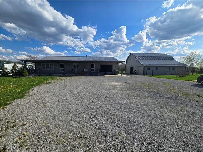 View of front of property featuring gravel driveway, a garage, and metal roof | Image 29