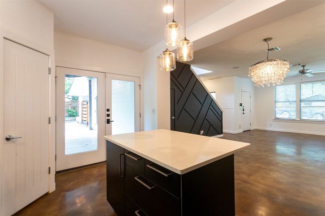 Kitchen with finished concrete flooring, dark cabinets, a center island, and a chandelier | Image 11