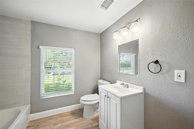 Full bath featuring vanity, wood finished floors, a bathtub, and healthy amount of natural light | Image 11