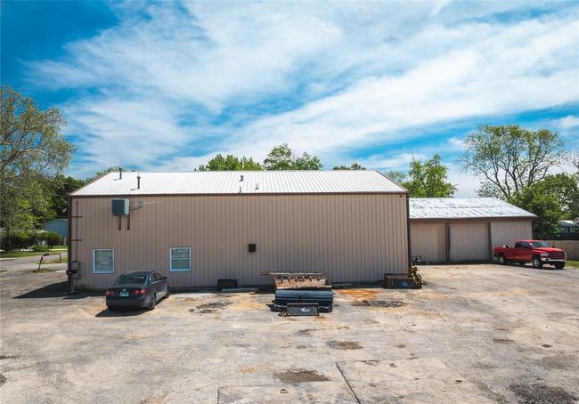 Back of property featuring metal roof, an outdoor structure, a garage, and a pole building | Image 8