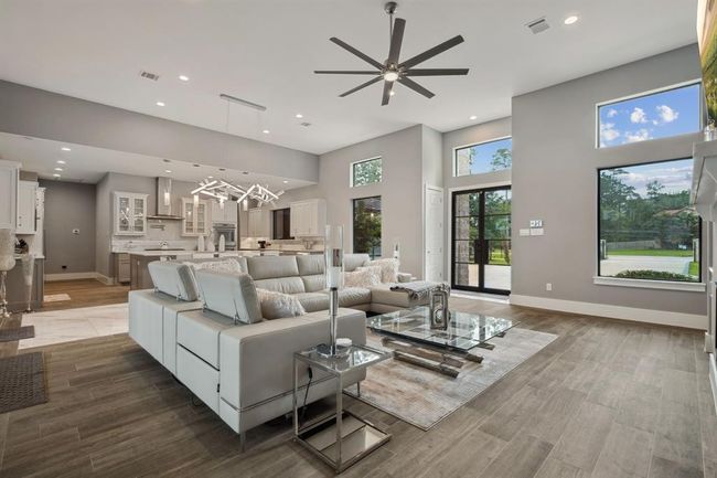 Featuring soaring ceilings and elegant neutral-toned flooring, this living room is adorned with striking lighting fixtures, exquisite built-ins, and expansive walls of windows that invite an abundance of natural light. | Image 8