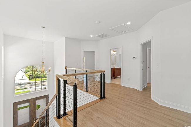 Corridor with an upstairs landing, light wood finished floors, a chandelier, and recessed lighting | Image 18