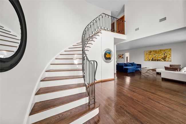 Stairway with a towering ceiling, visible vents, wood finished floors, and baseboards | Image 7