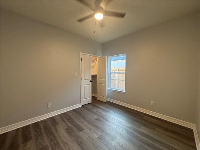 Unfurnished bedroom with dark wood finished floors, ceiling fan, and a closet | Image 23