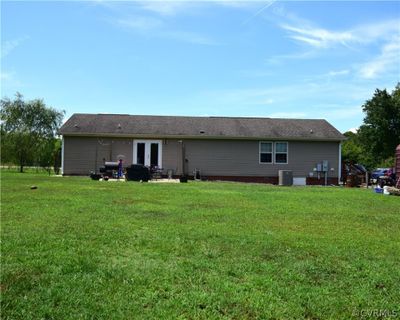 Rear view of house with central AC, french doors, and a lawn | Image 2