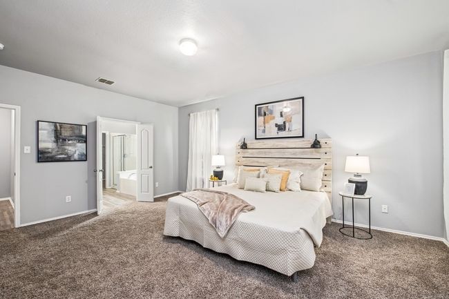Bedroom with visible vents, baseboards, connected bathroom, and carpet | Image 23