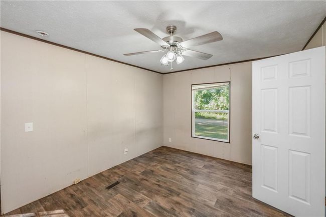 Unfurnished room with wood finished floors, a ceiling fan, ornamental molding, and a textured ceiling | Image 23