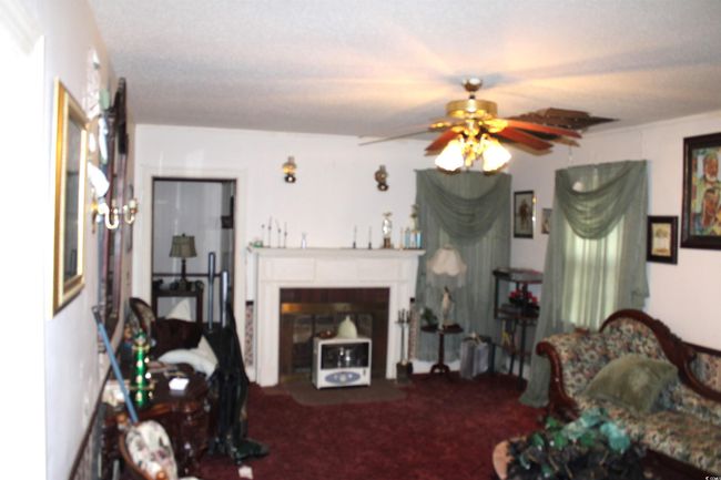 Carpeted living room featuring a ceiling fan and a fireplace | Image 8